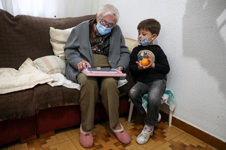 Florentina Martin, a 99 year-old woman who survived coronavirus, plays a digital puzzle with her great-grandson Pedro Valle at her home in Pinto, near Madrid, Spain. REUTERS/Sergio Perez